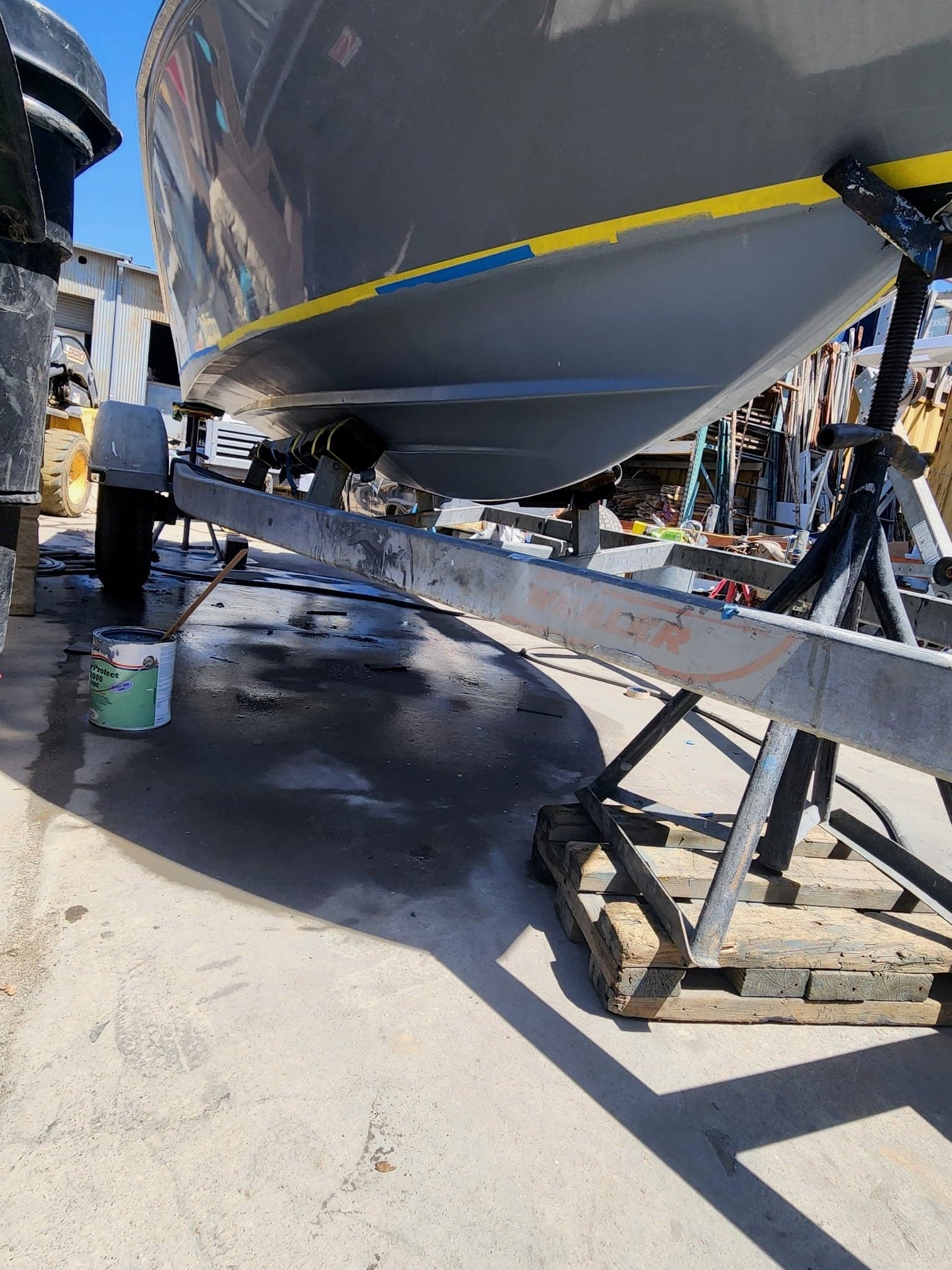 Boat hull on jack stands at the yard with fresh bottom paint visible