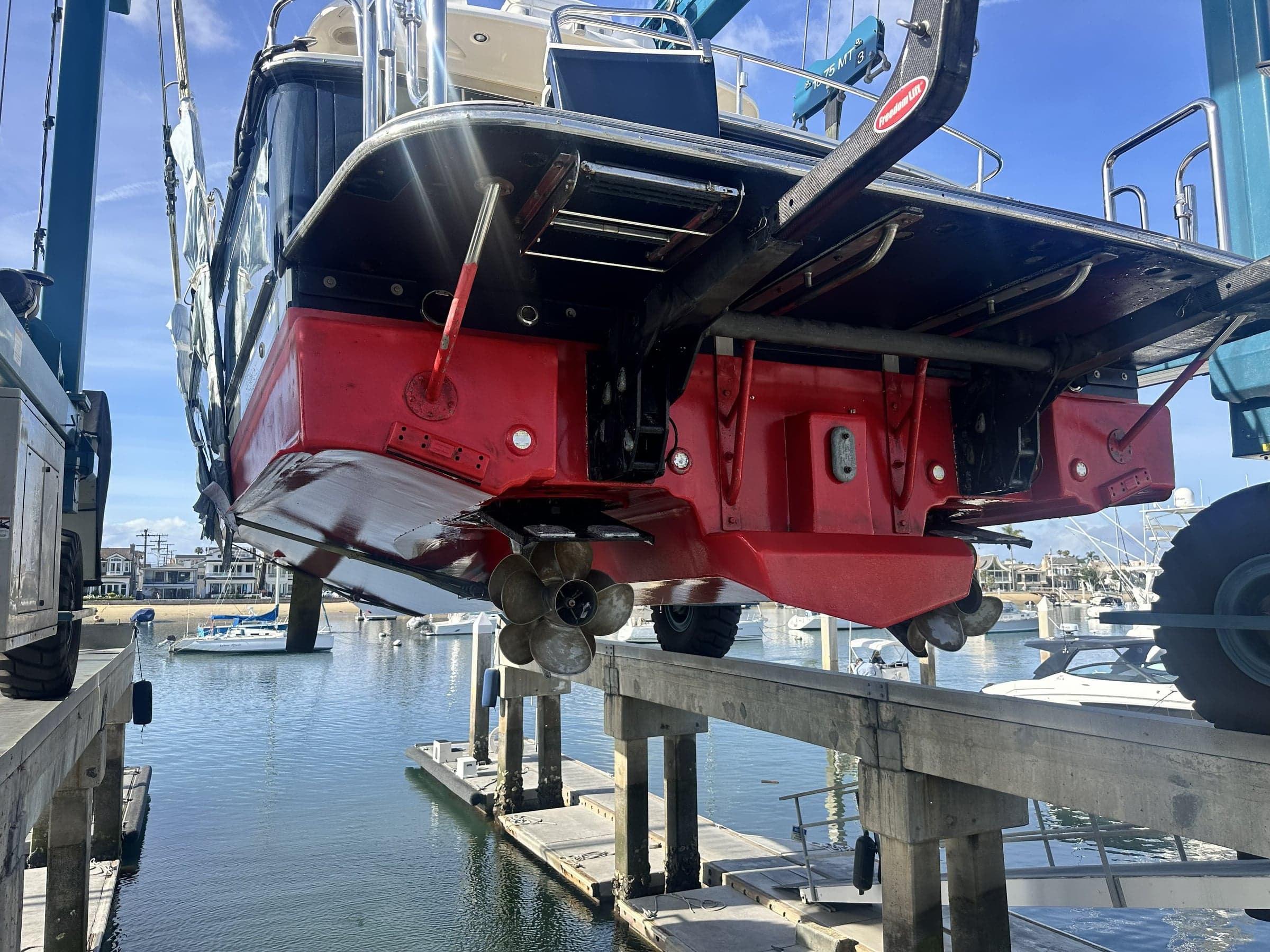 Sportfisher lifted on a travel lift, twin bronze propellers and rudders fully exposed