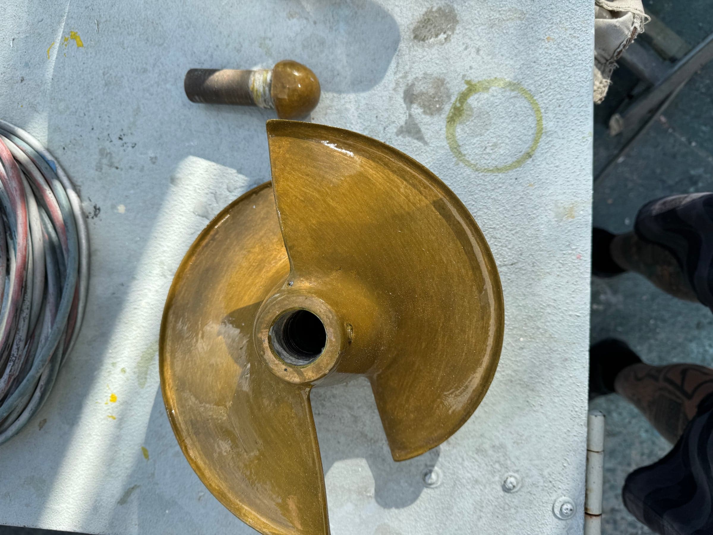 Two-blade bronze sailboat propeller with prop nut on a worker bench