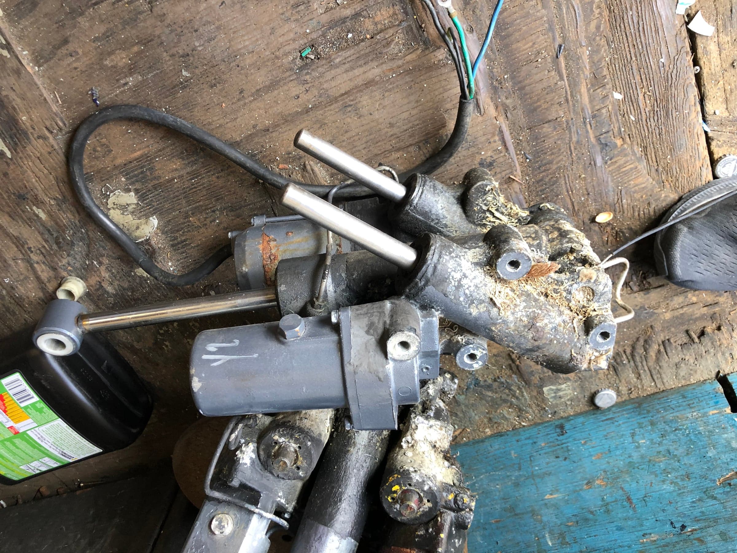 Disassembled outboard trim ram bracket with calcified white deposits and corrosion
